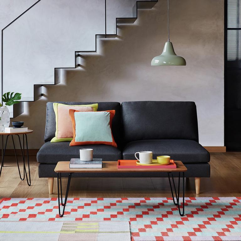 A black Habitat 2 seater velvet sofa in with wooden legs.