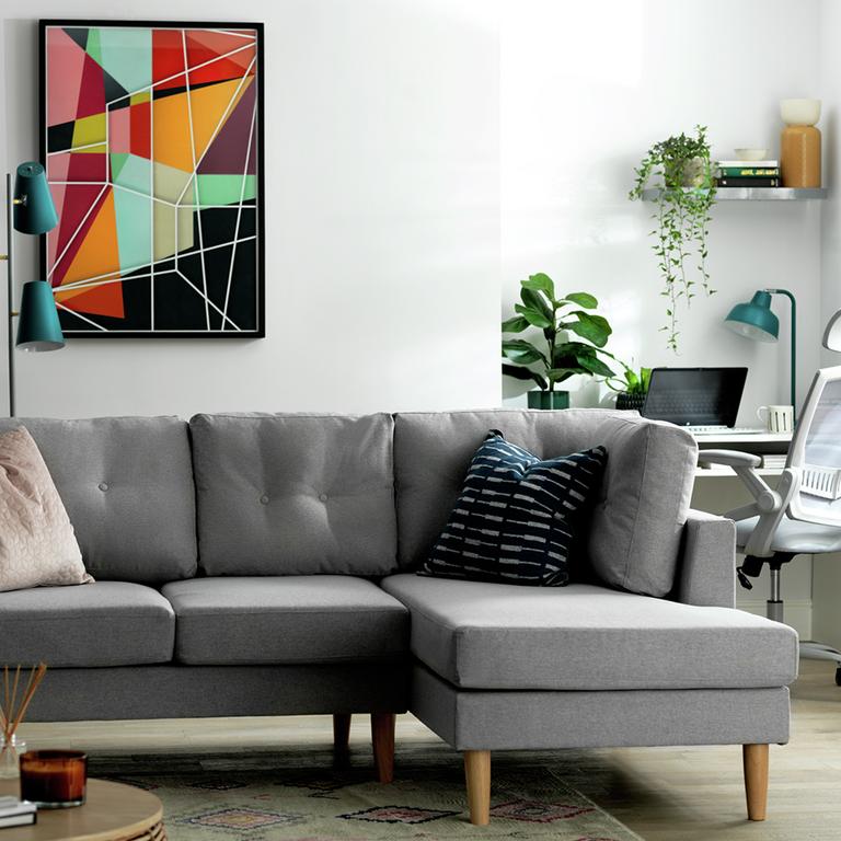 A grey Habitat right corner sofa with wooden legs placed in a white living room. 