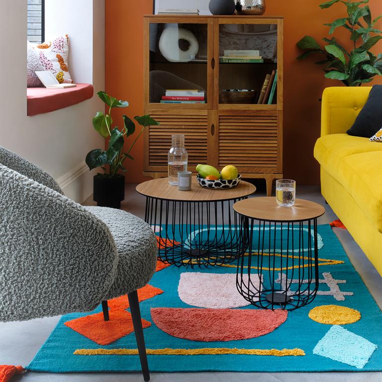 A travel-inspired living room with yellow sofa and colourful rug.