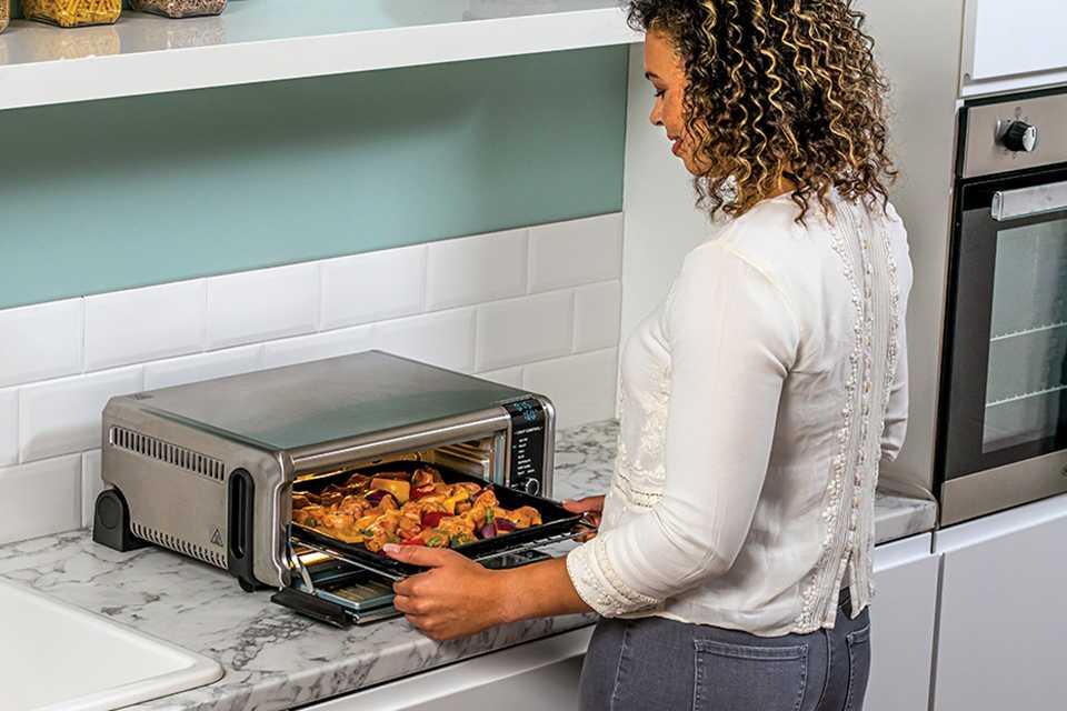 A woman roasting chopped vegetables in a Ninja mini oven.