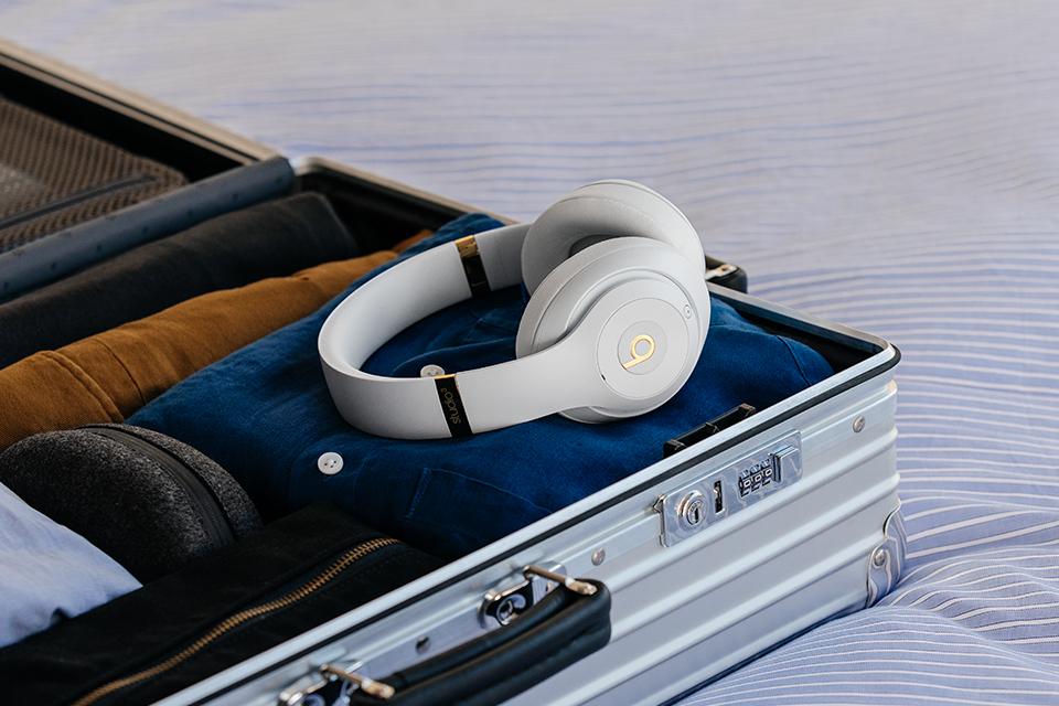 A pair of white Beats Studio 3 wireless headphones with folded clothes in a suitcase.