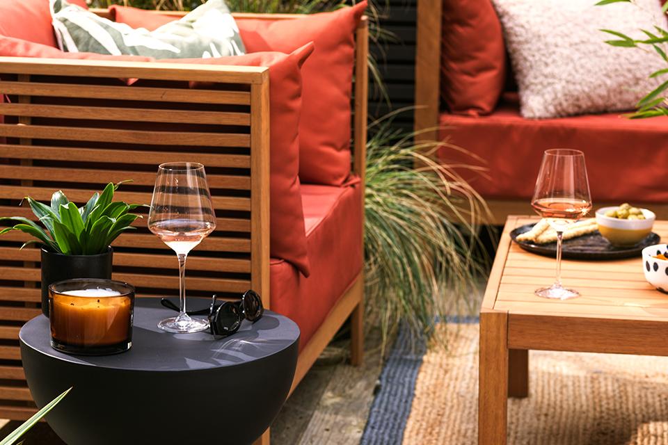 A Habitat black side table placed next to an outdoor sofa set displaying a wine glass and a succulent.