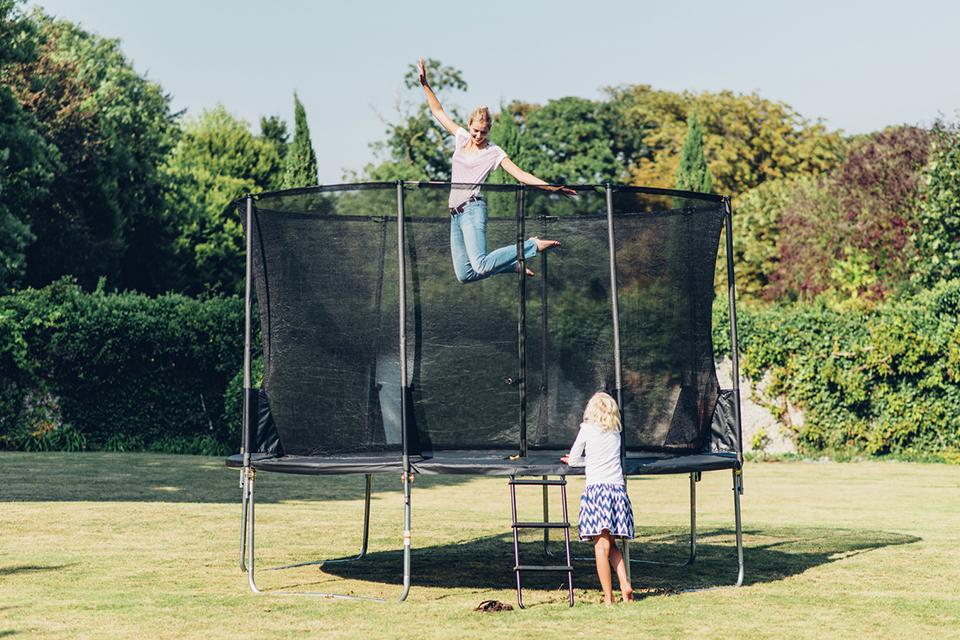 A mom and daughter playing on a trampoline.