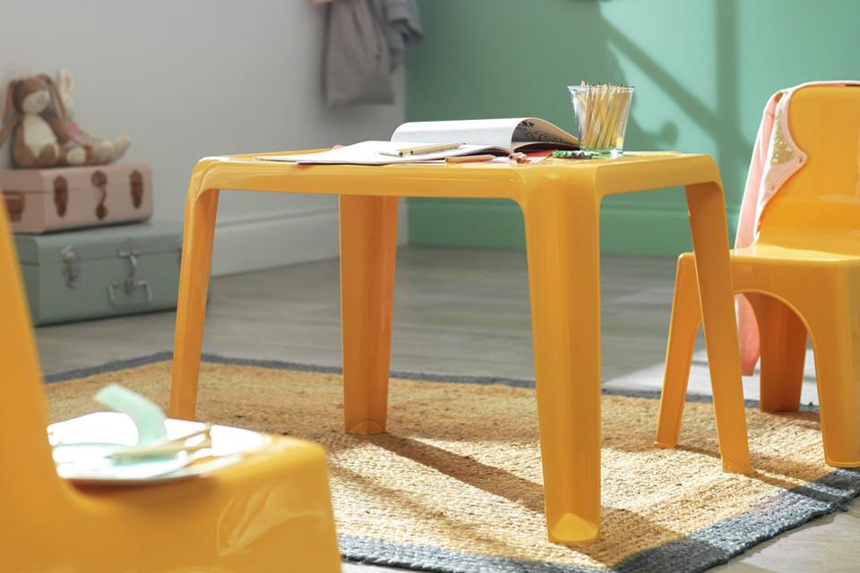A yellow table and chair set for kids in a green kid's room.