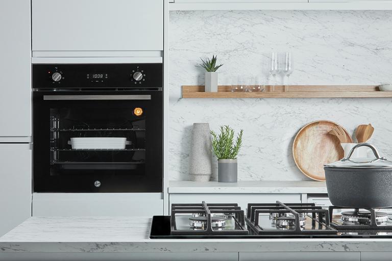An oven and a gas hob in a white kitchen.