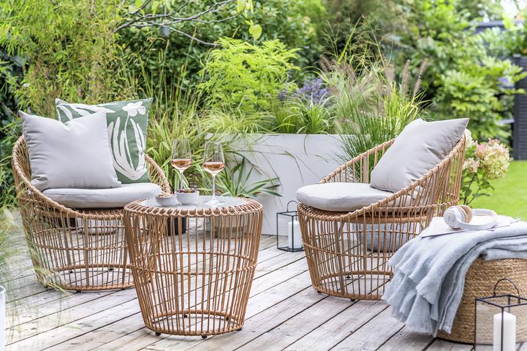 A 2 seater rattan garden bistro set in natural finish set on a patio.