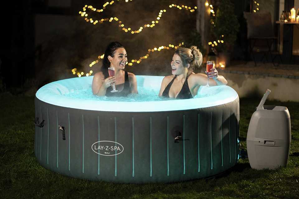 Two friends having a drink and enjoying in an inflatable spa hot tub.
