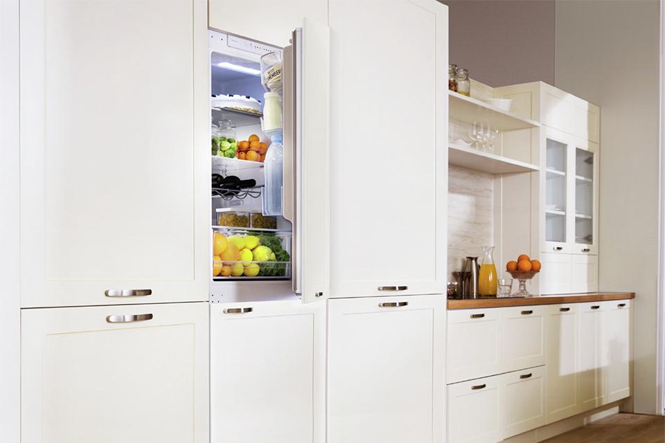 integrated fridge with door open in a white kitchen.