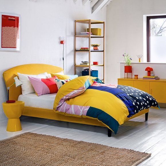 Yellow bedroom furniture with colourful bedding.