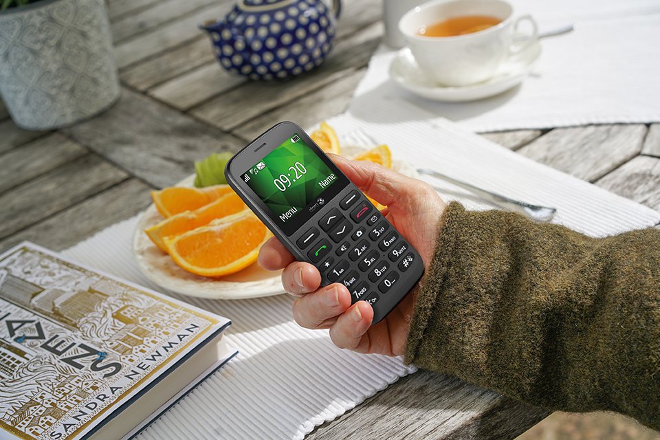 A hand holding a Doro 1380 feature phone in black.