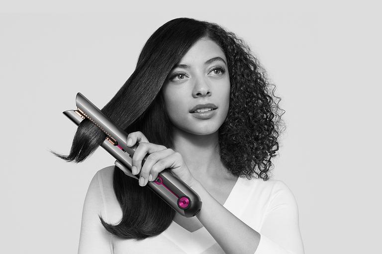 A girl using a Dyson Corrale to straighten her hair.
