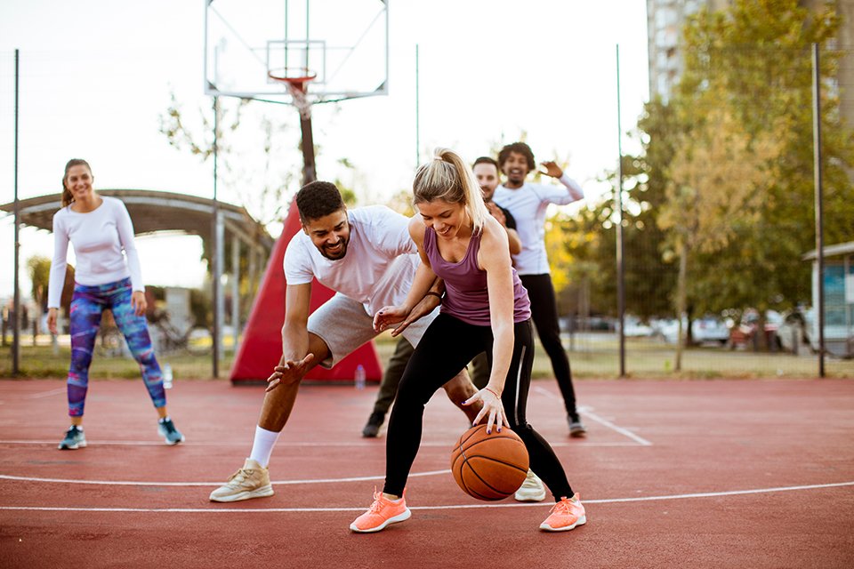 A group of friends playing basketball on a sunny day.