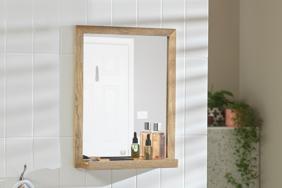 A Habitat Mango Wood Bathroom Mirror with Shelf in a bathroom.