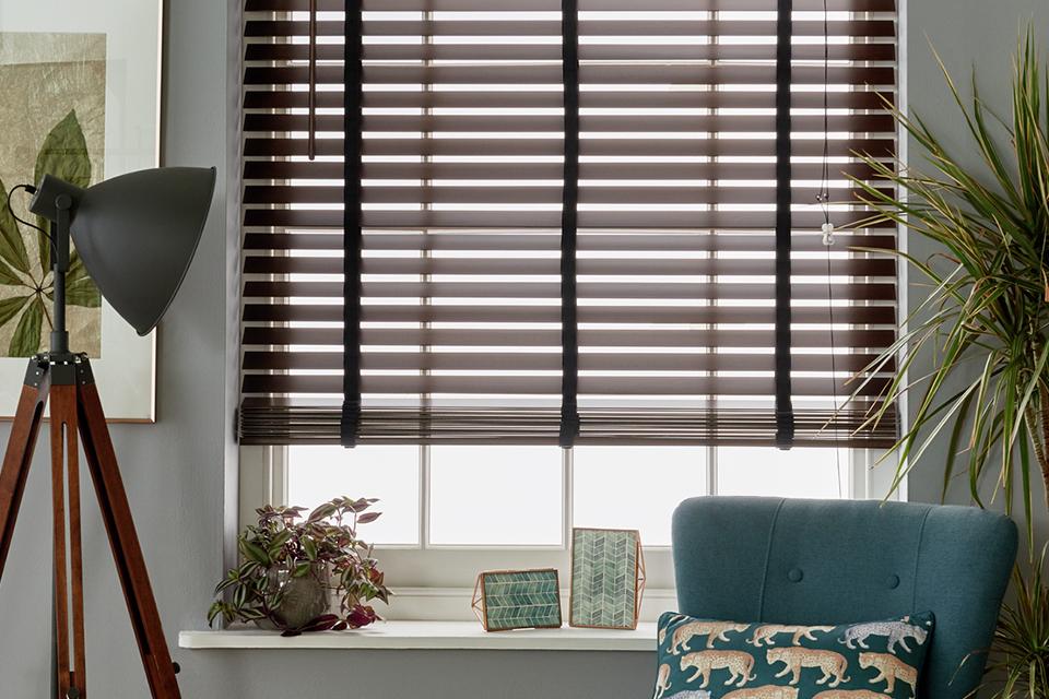 A wooden blind on the window of a living room.