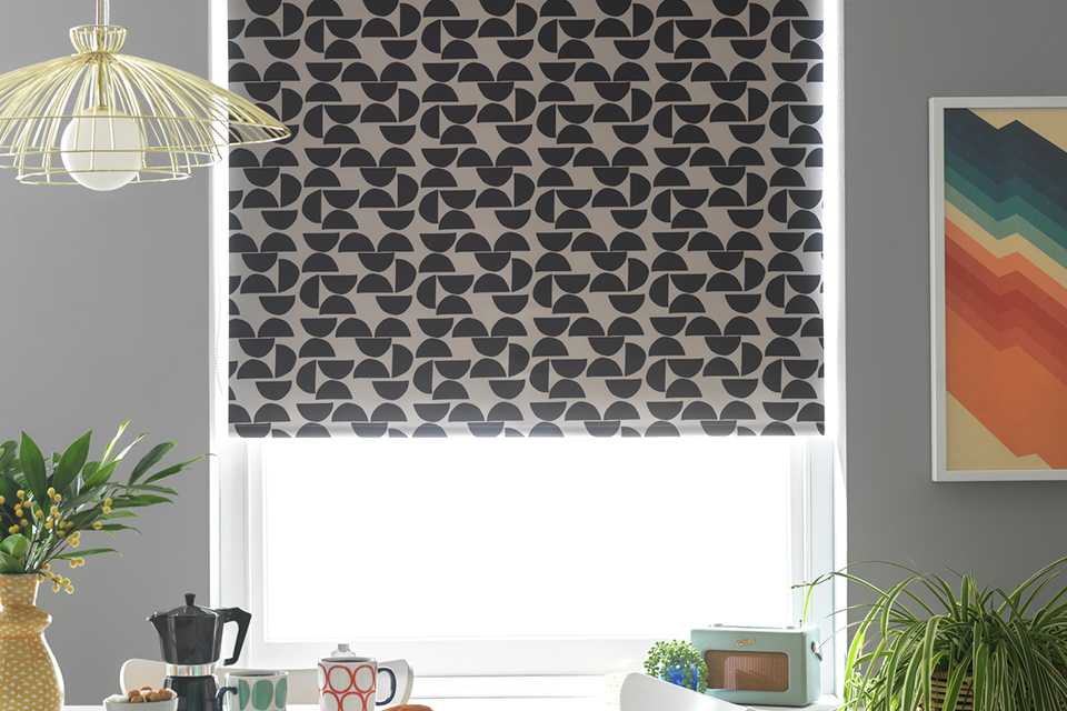 A Habitat mid-century geo printed blackout roller blind in a dining room's window.
