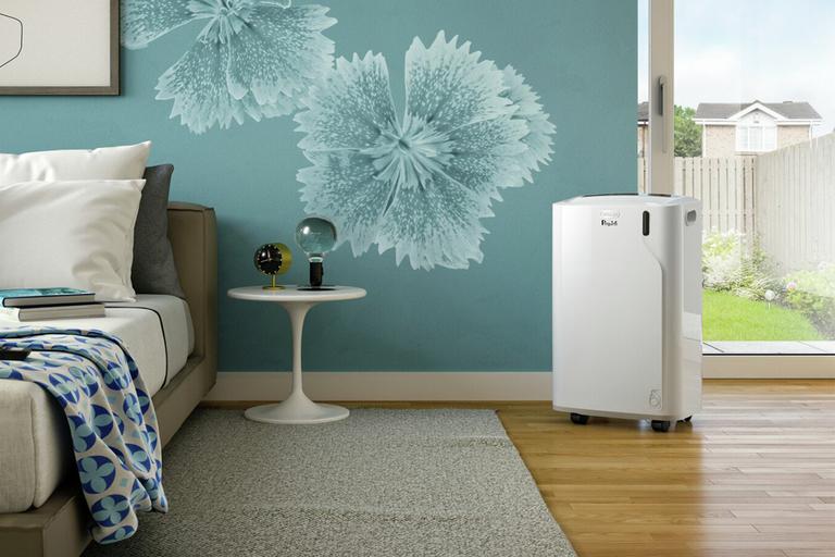 A De'Longhi Pinguino portable air conditioner in a bedroom.