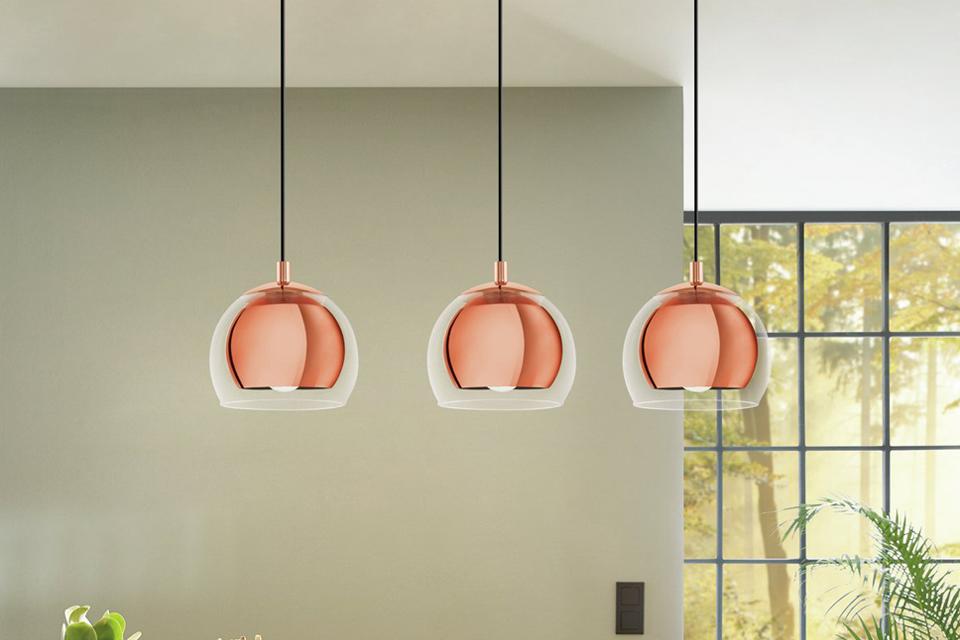 A set of 3 pendant lights in copper finish over a breakfast counter.