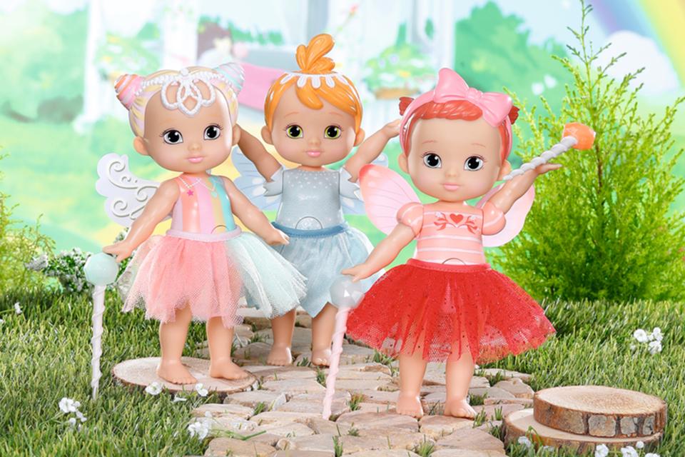 A set of 3 BABY born Storybook dolls in colourful outfits against a green forest backdrop.