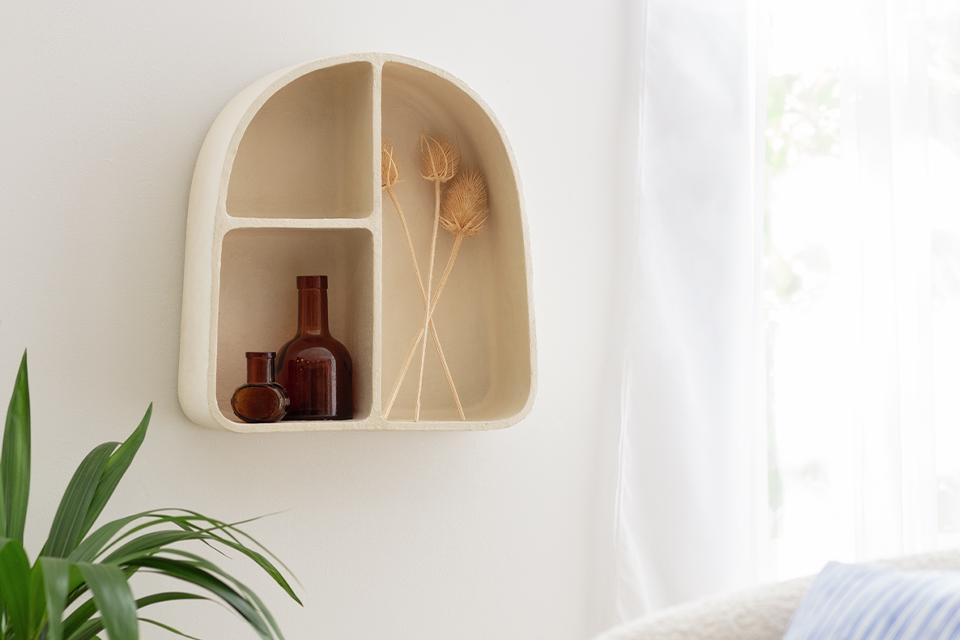 A Habitat mediterranean style wall shelving unit in off white in a white room.
