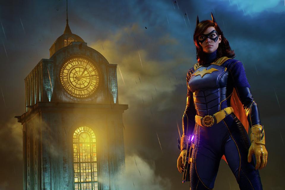 Batgirl stands in front of a lit up Belfry at night time.