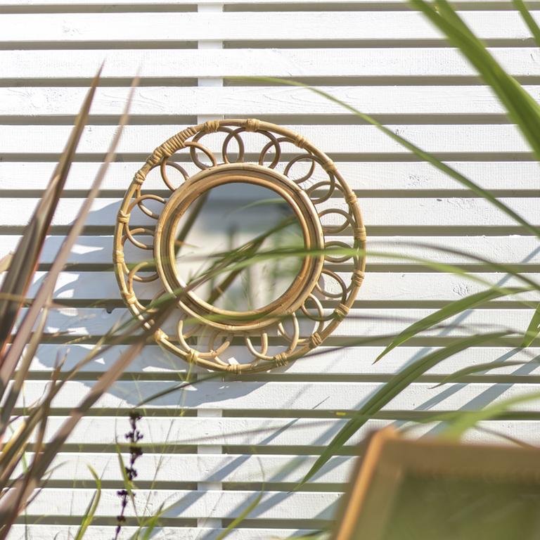 A Habitat faux rattan mirror in a garden.