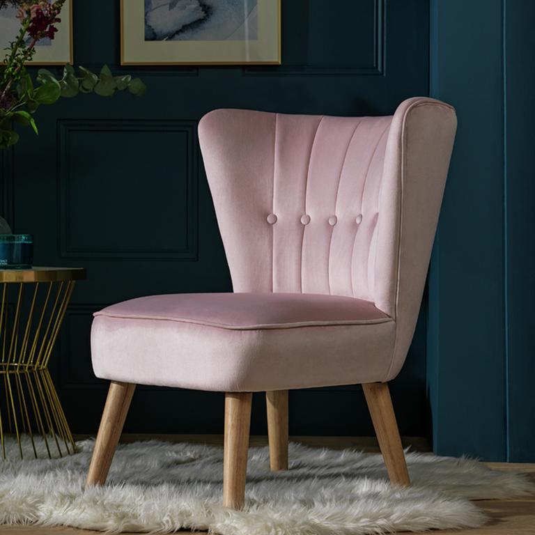 A Habitat fabric cocktail chair in pink with wooden legs. in a blue room. 