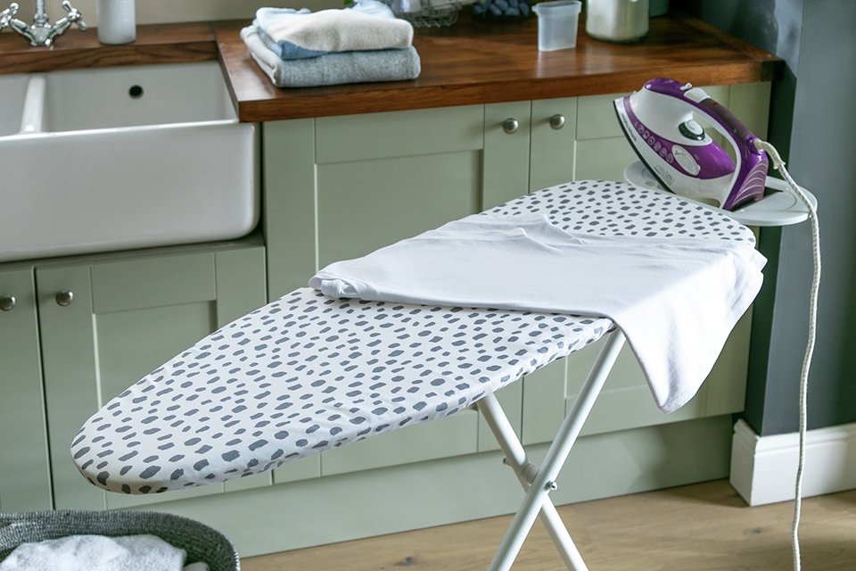 A Habitat ironing board with dalmation print placed in a utility room. 