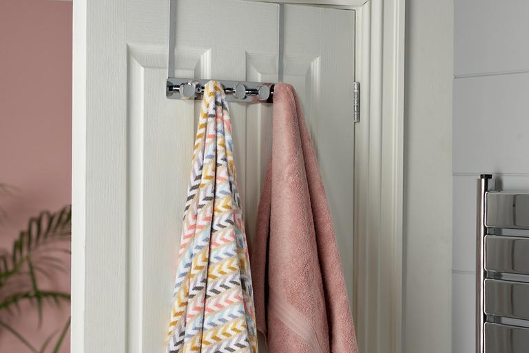 A pack of 5 over door round hooks in chrome finish with a pink and a multi-coloured towel hanging on it. 