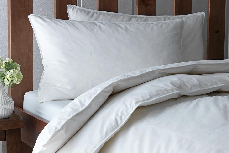 A wooden finish bed with white pillows and anti-allergy 4.5 tog duvet on it. 