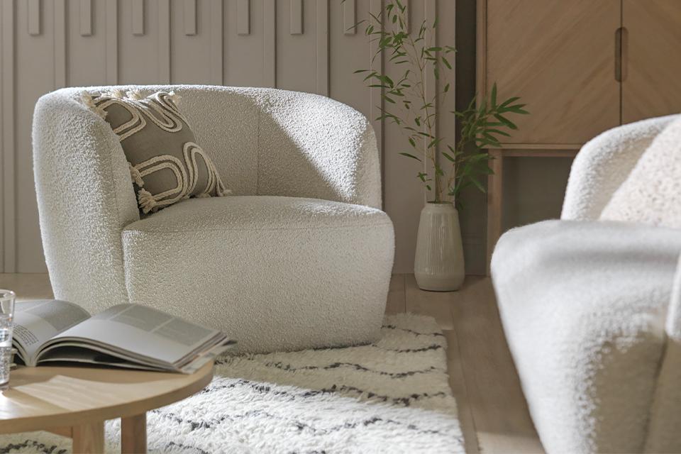 A Habitat boucle armchair in white placed in a living room next to a white boucle sofa. 