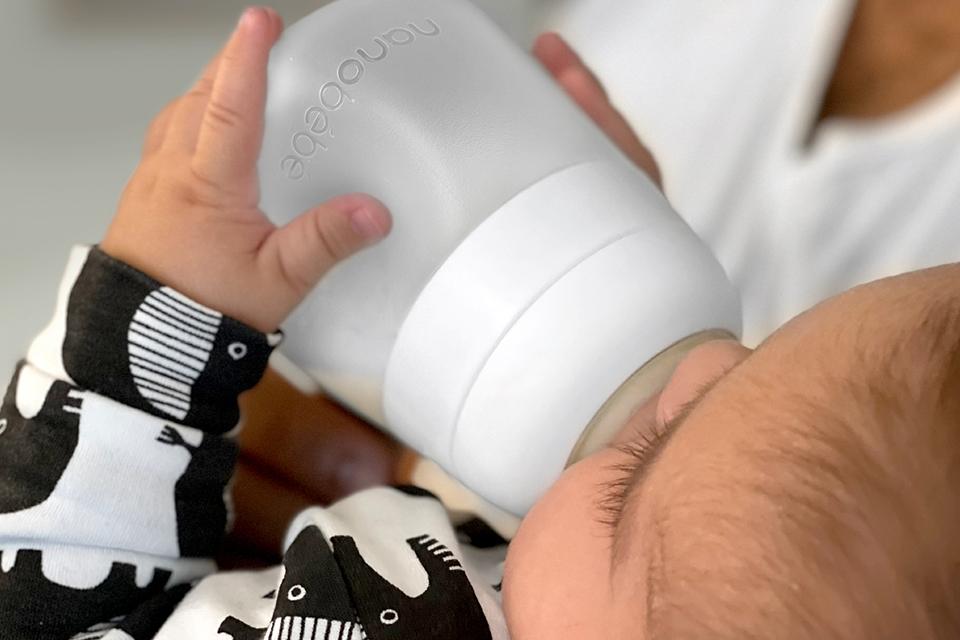 A close up image of a baby drinking from a Nanobebe flexy silicone baby bottle.