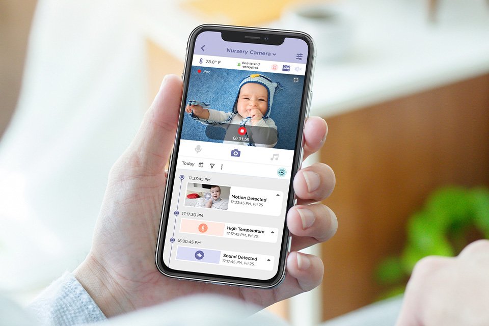 A parent watching their baby through a mobile paired with the baby monitor.