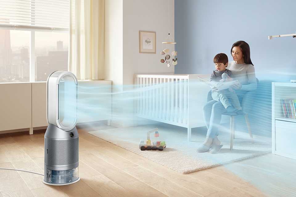 A mother and toddler in the kid's room sitting opposite an air purifier.