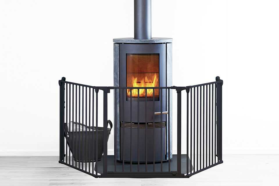 A BabyDan black safety gate covering a fireplace.