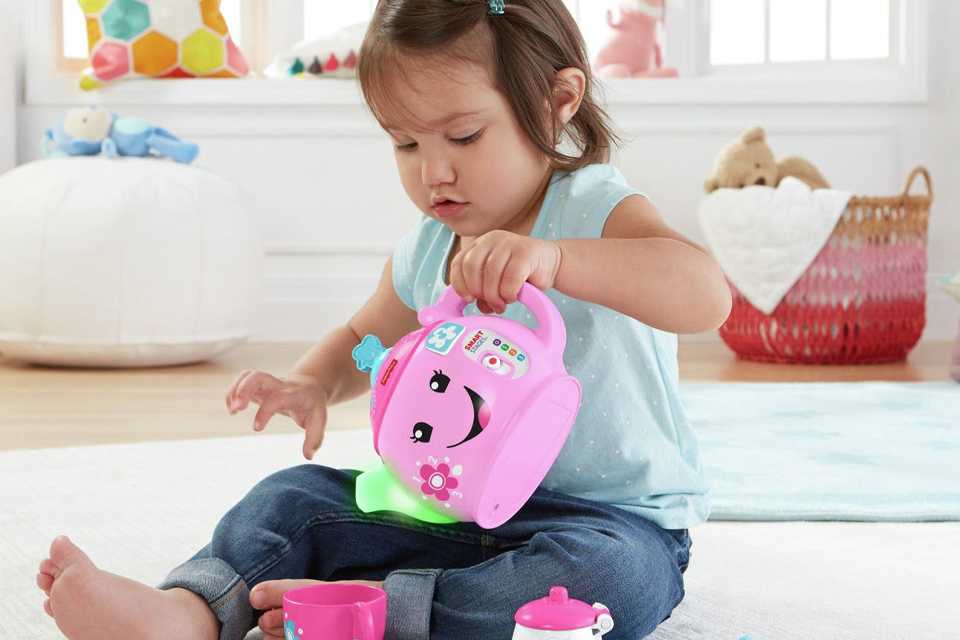 A toddler playing with a toy tea set.