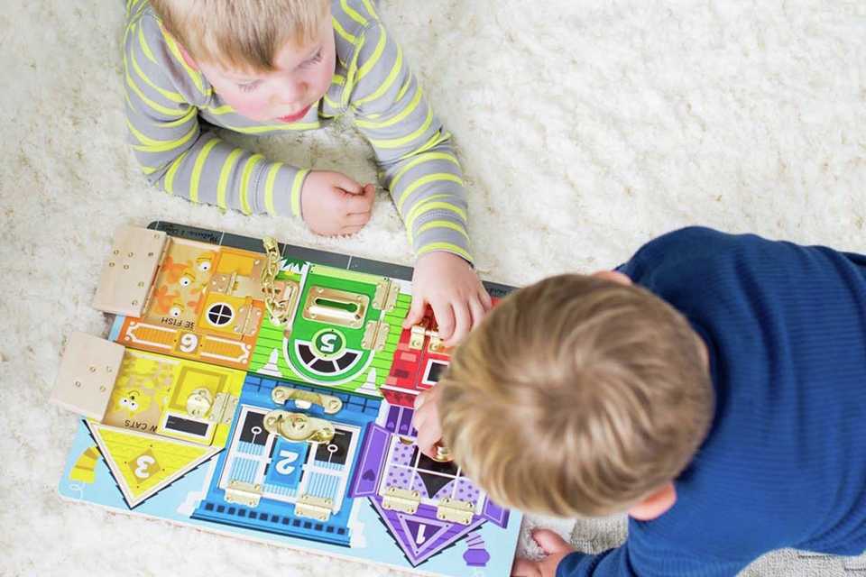 Two friends playing with Melissa & Doug latches board.