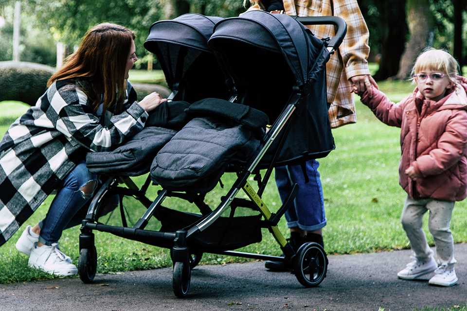 A woman on a walk with her kids in Red Kite Push Me double stroller.
