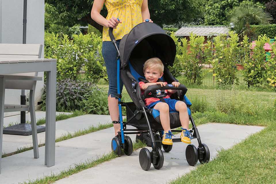 A mother standing outside on her patio with her toddler sitting in a Chicco Stone Echo stroller.