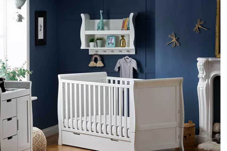 A white cot bed and a white changing unit in a kid's bedroom.