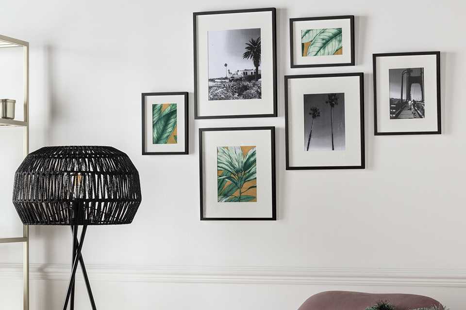 A pack of 6 gallery photo frames in black hung over a pink armchair. 