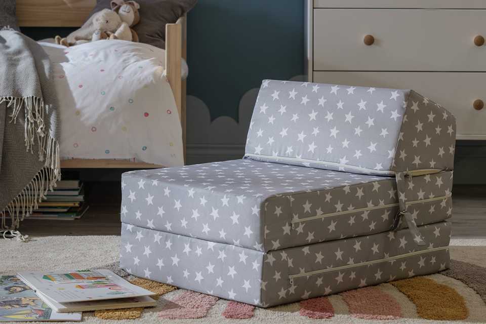A Habitat kid's grey stars print chair bed placed on a rug in a kid's room.