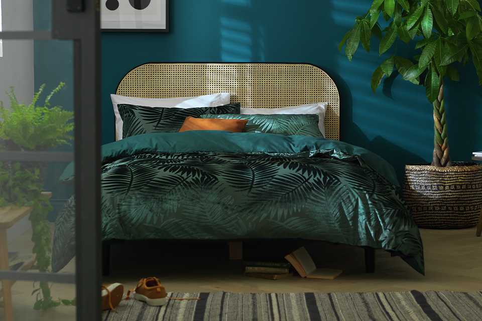 A Habitat kingsize wooden bed frame with velvet green bedding set.