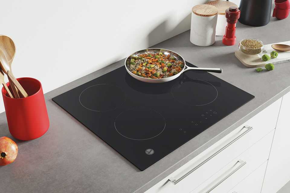 A pan on a Hoover black induction hob in a modern kitchen.