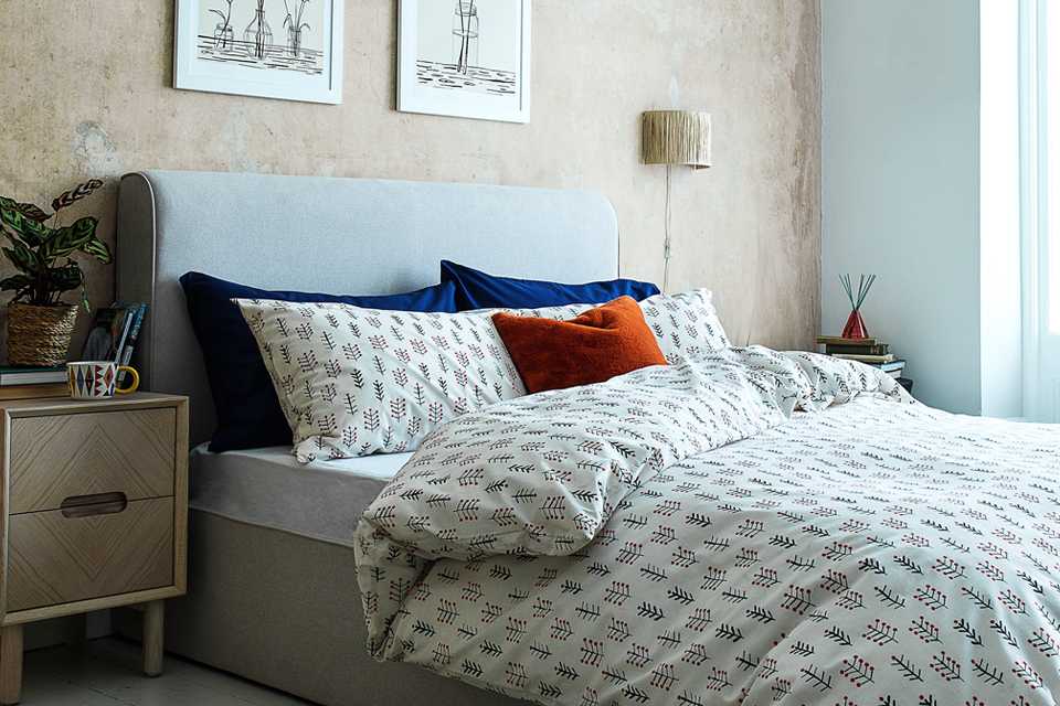 A guest bedroom with printed white duvet and colourful pillows on the bed.