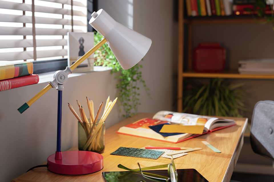 A Habitat Jean colour block desk lamp on a table near the window.