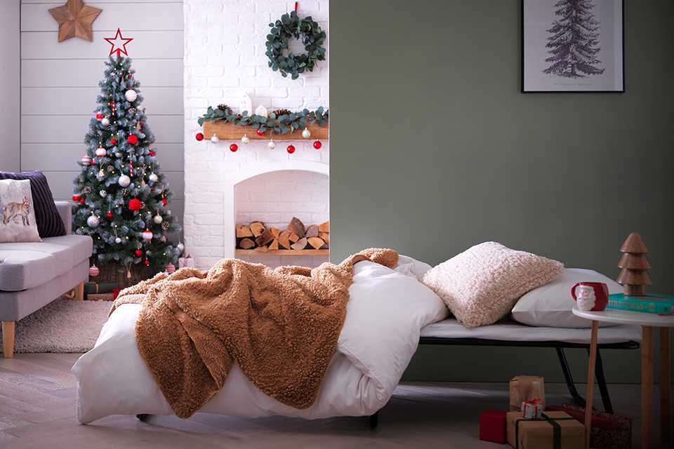 An air bed with a cushion, duvet and a blanket on it.