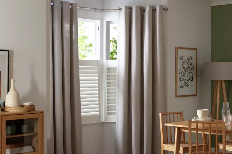 A Habitat linen-look blackout eyelet curtain in oatmeal colour in a living room window near the sideboard.