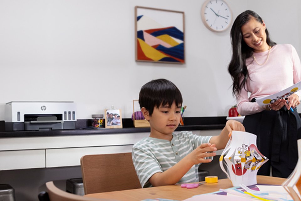 A young boy an a woman making paper lanterns with an HP printer in their background.