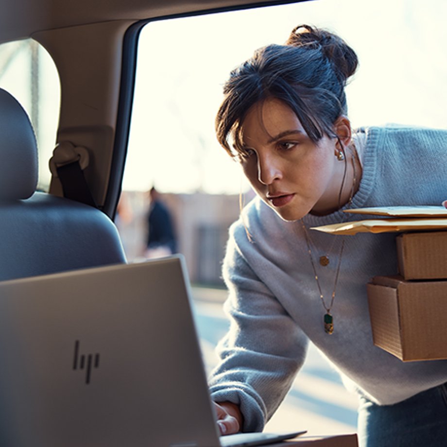 A girl looking at an HP laptop inside a car.