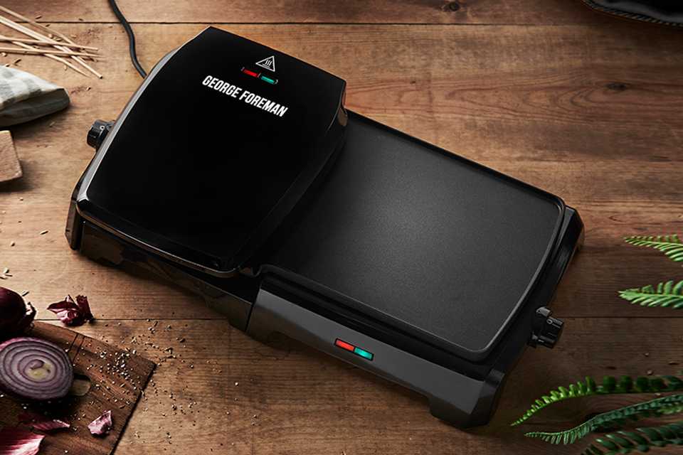 A black George Foreman large variable temp grill & griddle on a wooden surface.